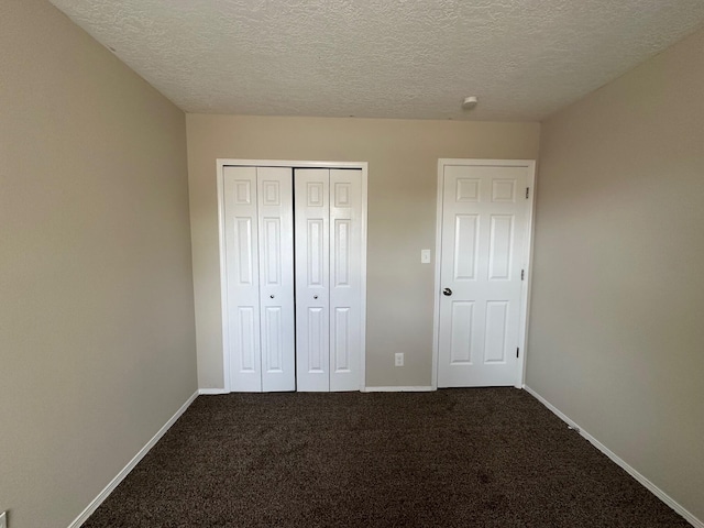 unfurnished bedroom featuring carpet floors, a textured ceiling, and a closet