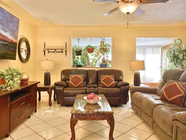 living room with ceiling fan, light tile patterned floors, and a textured ceiling