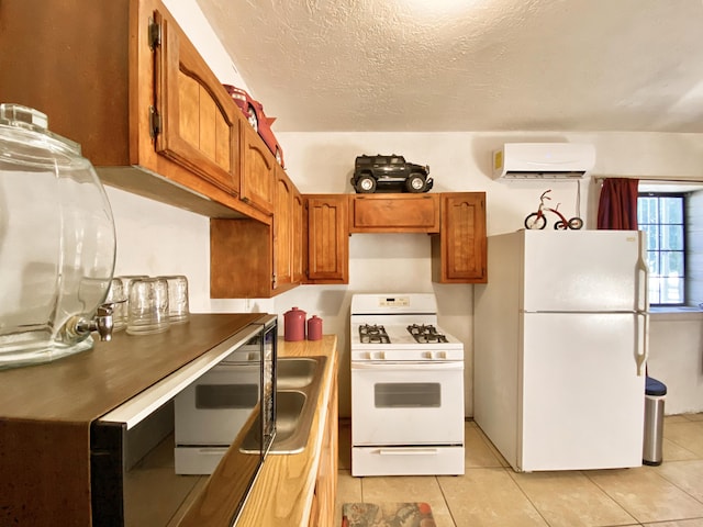 kitchen featuring sink, an AC wall unit, a textured ceiling, white appliances, and light tile patterned floors