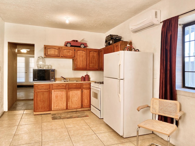 kitchen featuring a textured ceiling, white appliances, sink, an AC wall unit, and light tile patterned flooring