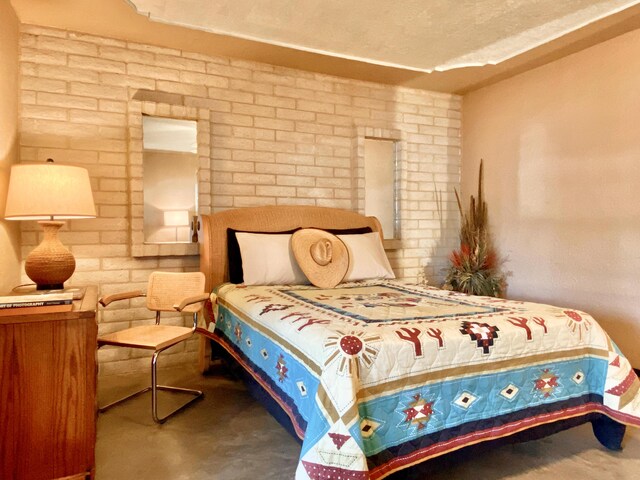 bedroom featuring a textured ceiling and brick wall