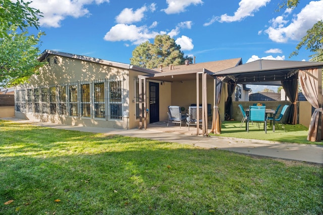 rear view of house featuring a gazebo, a patio, and a lawn