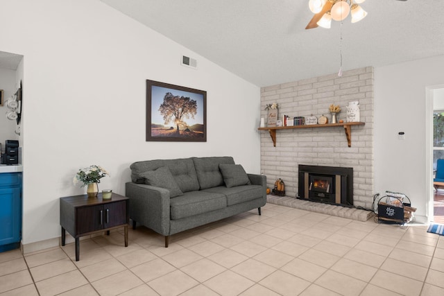 tiled living room featuring a brick fireplace, ceiling fan, a textured ceiling, and vaulted ceiling