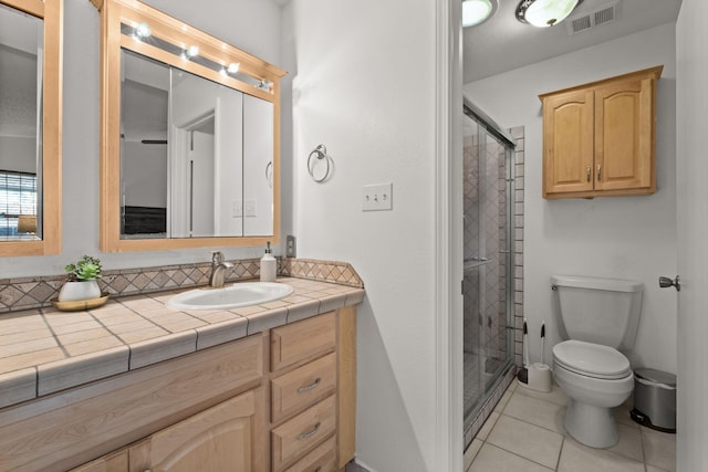 bathroom with tile patterned flooring, vanity, toilet, and a shower with shower door