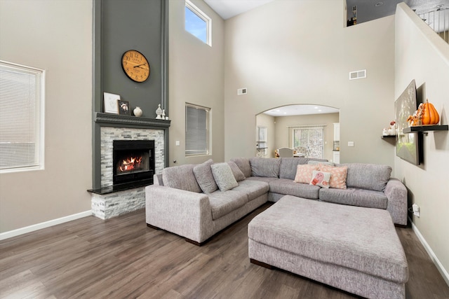 living room featuring a fireplace, dark hardwood / wood-style floors, and a towering ceiling