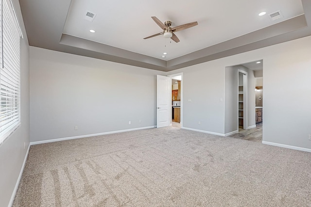 carpeted empty room featuring a tray ceiling and ceiling fan