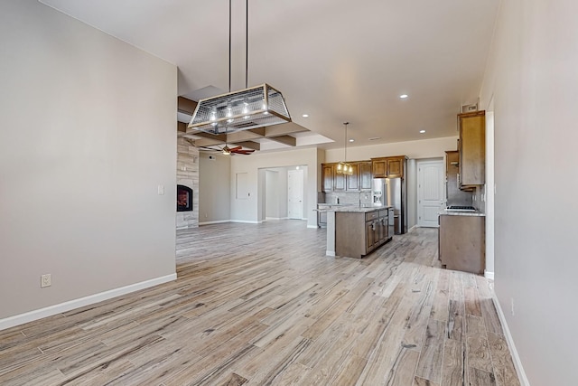 kitchen featuring light wood-type flooring, stainless steel fridge, decorative light fixtures, and a center island