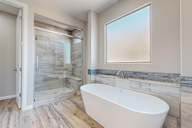 bathroom featuring a wealth of natural light, wood-type flooring, and separate shower and tub