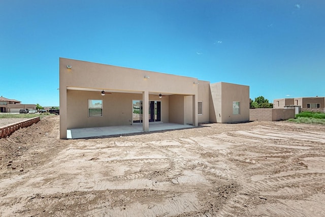 rear view of property with ceiling fan and a patio area