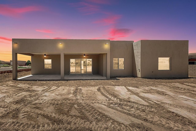 back house at dusk featuring ceiling fan and a patio area