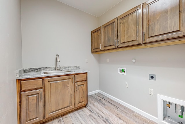 clothes washing area featuring cabinets, light hardwood / wood-style floors, sink, hookup for an electric dryer, and hookup for a gas dryer