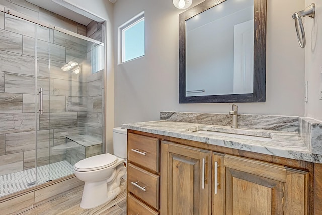 bathroom featuring hardwood / wood-style floors, a shower with shower door, vanity, and toilet