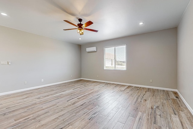 spare room with light hardwood / wood-style floors, ceiling fan, and a wall mounted air conditioner