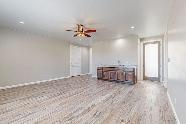 unfurnished living room featuring light wood-type flooring, sink, and ceiling fan