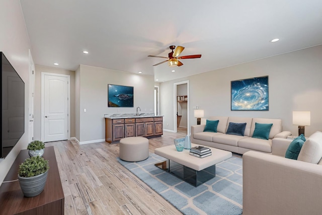 living room featuring light wood-type flooring, sink, and ceiling fan