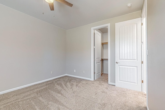 unfurnished bedroom with a spacious closet, light carpet, ceiling fan, and a closet