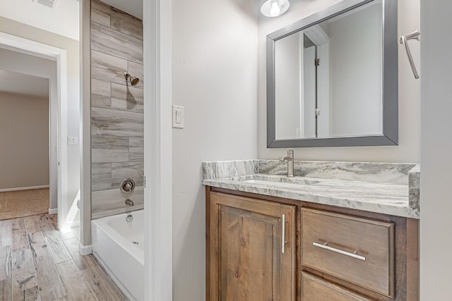 bathroom featuring wood-type flooring, vanity, and tiled shower / bath combo