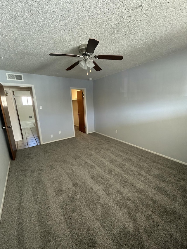 unfurnished bedroom featuring a walk in closet, ceiling fan, a closet, and dark carpet