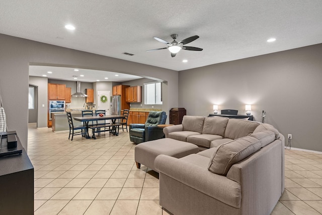 living room with a textured ceiling, light tile patterned flooring, and ceiling fan