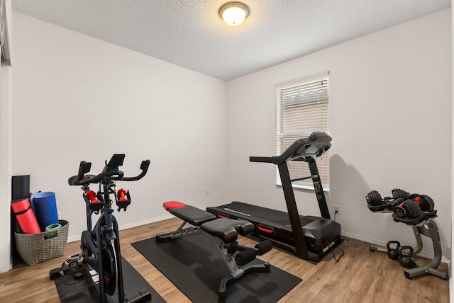 exercise area featuring light hardwood / wood-style floors and a textured ceiling