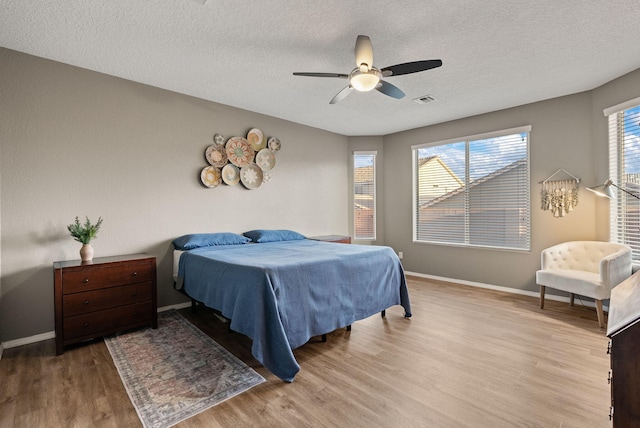 bedroom featuring ceiling fan, a textured ceiling, and light hardwood / wood-style flooring