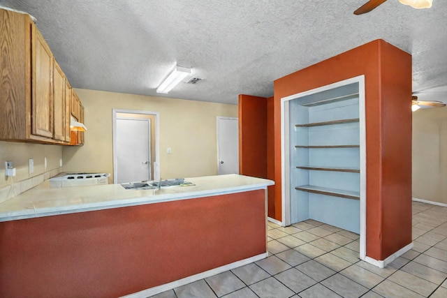 kitchen with a textured ceiling, kitchen peninsula, light tile patterned flooring, and ceiling fan