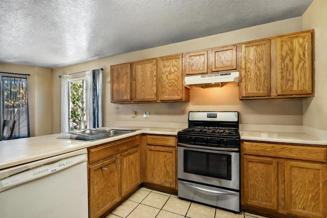 kitchen featuring white dishwasher, stainless steel gas range oven, a textured ceiling, and light tile patterned floors