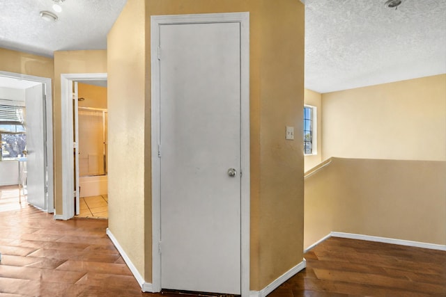 hall featuring a textured ceiling and hardwood / wood-style flooring