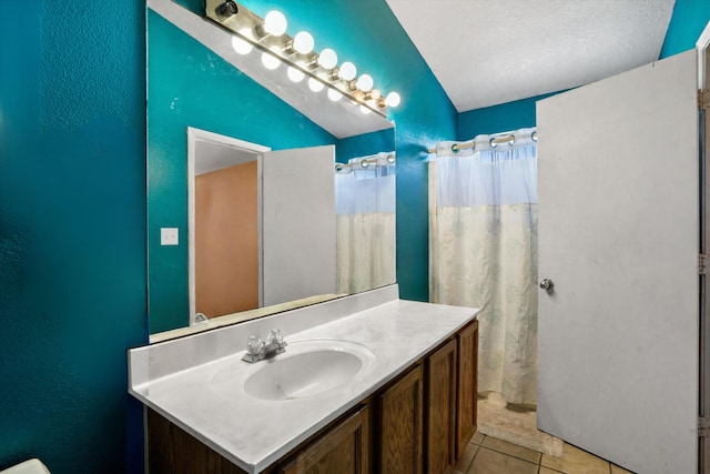 bathroom with lofted ceiling, tile patterned flooring, curtained shower, a textured ceiling, and vanity