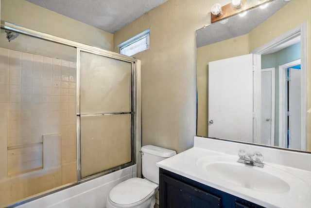 full bathroom featuring toilet, vanity, a textured ceiling, and combined bath / shower with glass door