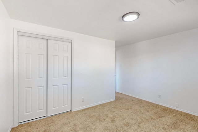 unfurnished bedroom featuring light carpet and a closet