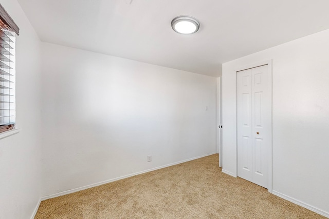 unfurnished bedroom featuring light colored carpet and a closet