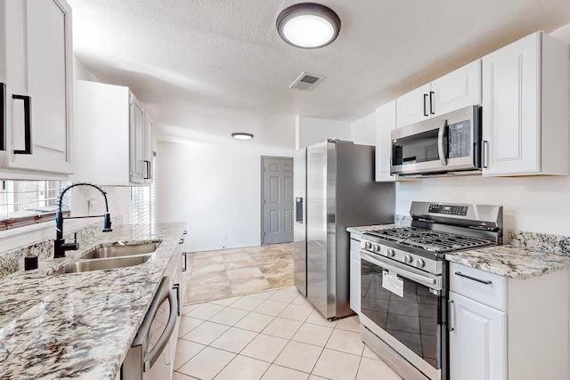 kitchen with light stone countertops, sink, a textured ceiling, white cabinets, and appliances with stainless steel finishes