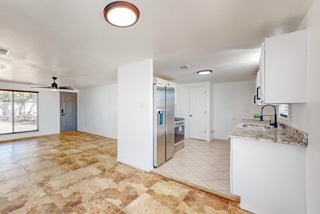 kitchen featuring ceiling fan, sink, light stone countertops, white cabinets, and appliances with stainless steel finishes