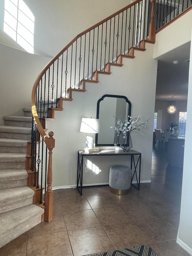 staircase with tile patterned floors, a high ceiling, and a chandelier