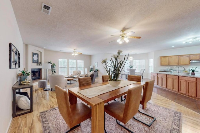 dining area with ceiling fan, light hardwood / wood-style floors, and a textured ceiling