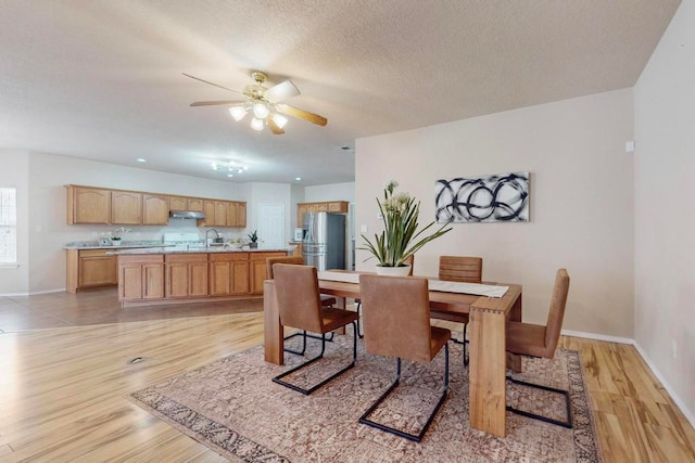 dining room with ceiling fan, sink, light hardwood / wood-style floors, and a textured ceiling