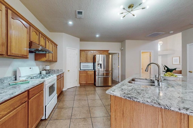 kitchen featuring a textured ceiling, light stone countertops, sink, and white appliances