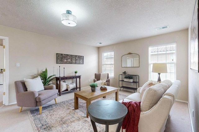 living room with a healthy amount of sunlight, light colored carpet, and a textured ceiling