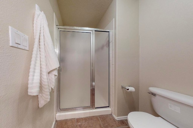 bathroom featuring toilet, a textured ceiling, tile patterned floors, and a shower with door