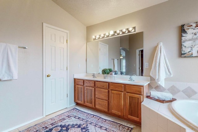 bathroom with vanity, vaulted ceiling, tile patterned flooring, a textured ceiling, and tiled bath