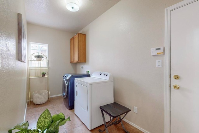 laundry area featuring cabinets, light tile patterned floors, and washing machine and dryer