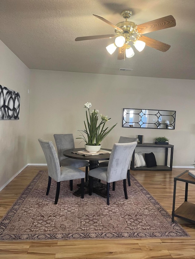 dining space with hardwood / wood-style flooring, ceiling fan, and a textured ceiling