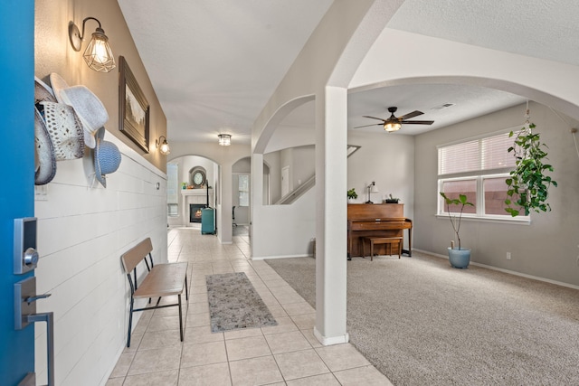 carpeted foyer entrance with ceiling fan and a textured ceiling