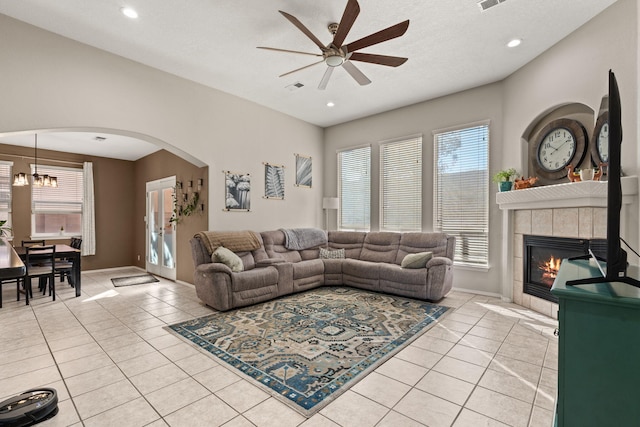 tiled living room with ceiling fan and a tile fireplace