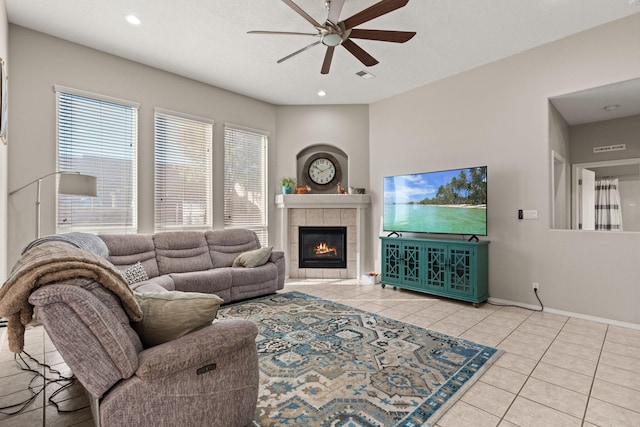 tiled living room with ceiling fan and a fireplace