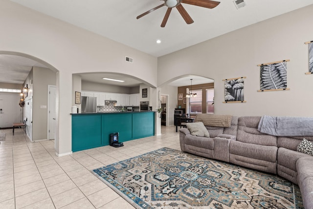 living room with light tile patterned flooring and ceiling fan with notable chandelier