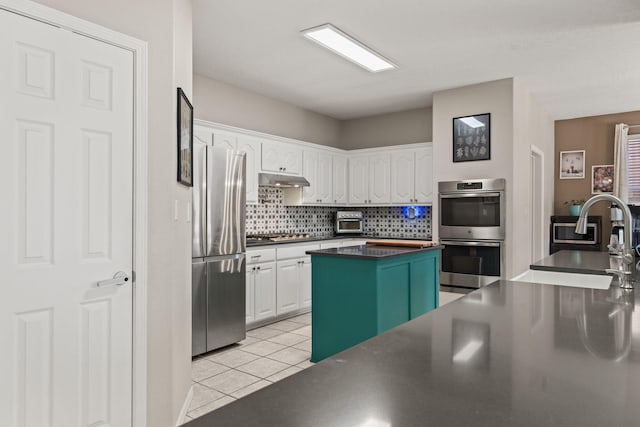 kitchen with sink, a center island, light tile patterned floors, stainless steel appliances, and white cabinets