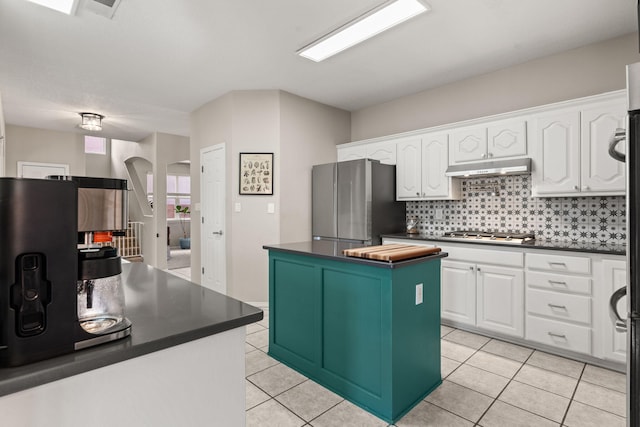 kitchen with stainless steel appliances, a center island, light tile patterned floors, and white cabinets