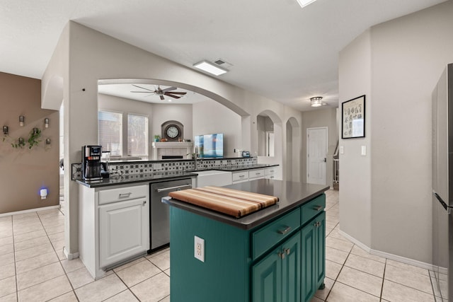 kitchen featuring ceiling fan, appliances with stainless steel finishes, a center island, white cabinets, and light tile patterned flooring